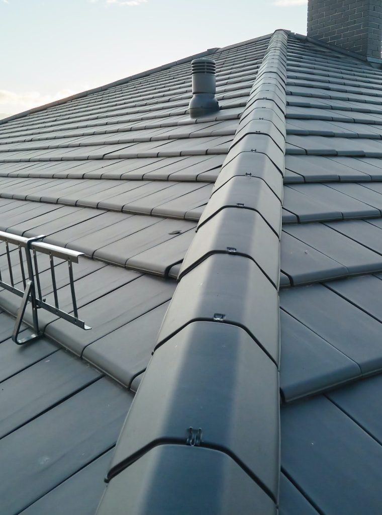 Closeup of house roof top covered with ceramic shingles. Tiled covering of building